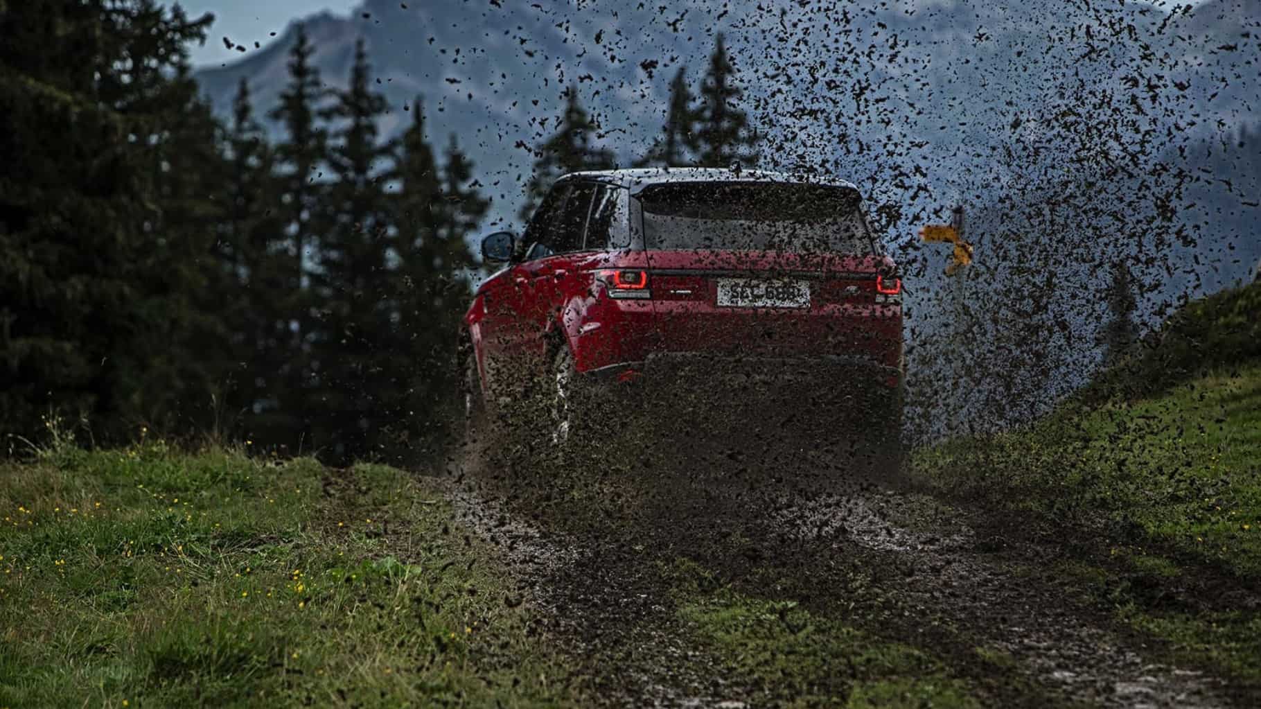 Range Rover in red driving in mud back view